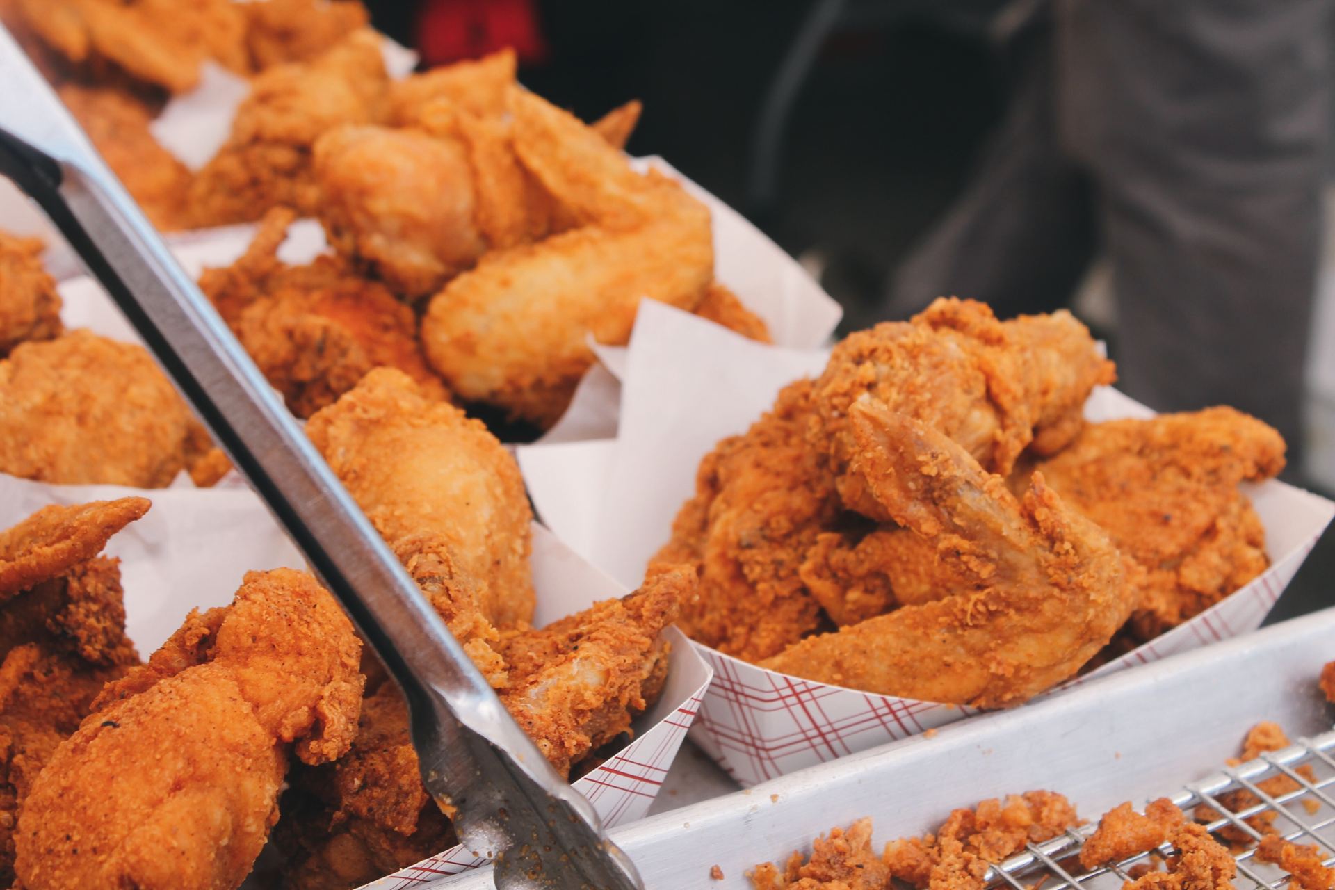 Crispy fried chicken wings piled in paper trays
